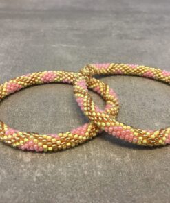 Roll-on armbånd som passer til næsten alle kvinder. Kvindegrupper i Nepal, Kathmandu Valley, udstyres med glasperler og bomuldsgarn, så de i deres fritid kan hækler disse smukke perlearmbånd. Den ekstra indtægt går bl.a. til at sende kvindernes børn i skole. Hvert armbånd er et unikt resultat af kvindernes håndarbejde og varierer i farvekombinationer og mønstre.