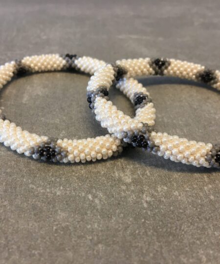 Roll-on armbånd som passer til næsten alle kvinder. Kvindegrupper i Nepal, Kathmandu Valley, udstyres med glasperler og bomuldsgarn, så de i deres fritid kan hækler disse smukke perlearmbånd. Den ekstra indtægt går bl.a. til at sende kvindernes børn i skole. Hvert armbånd er et unikt resultat af kvindernes håndarbejde og varierer i farvekombinationer og mønstre.