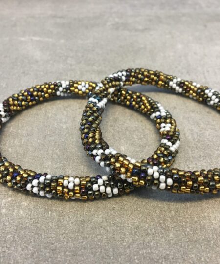 Roll-on armbånd som passer til næsten alle kvinder. Kvindegrupper i Nepal, Kathmandu Valley, udstyres med glasperler og bomuldsgarn, så de i deres fritid kan hækler disse smukke perlearmbånd. Den ekstra indtægt går bl.a. til at sende kvindernes børn i skole. Hvert armbånd er et unikt resultat af kvindernes håndarbejde og varierer i farvekombinationer og mønstre.