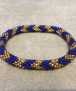 Roll-on armbånd som passer til næsten alle kvinder. Kvindegrupper i Nepal, Kathmandu Valley, udstyres med glasperler og bomuldsgarn, så de i deres fritid kan hækler disse smukke perlearmbånd. Den ekstra indtægt går bl.a. til at sende kvindernes børn i skole. Hvert armbånd er et unikt resultat af kvindernes håndarbejde og varierer i farvekombinationer og mønstre.