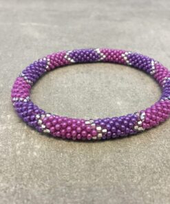 Roll-on armbånd som passer til næsten alle kvinder. Kvindegrupper i Nepal, Kathmandu Valley, udstyres med glasperler og bomuldsgarn, så de i deres fritid kan hækler disse smukke perlearmbånd. Den ekstra indtægt går bl.a. til at sende kvindernes børn i skole. Hvert armbånd er et unikt resultat af kvindernes håndarbejde og varierer i farvekombinationer og mønstre.