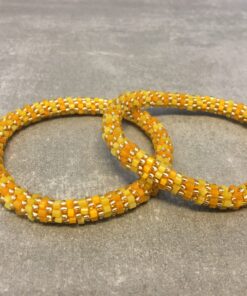 Roll-on armbånd som passer til næsten alle kvinder. Kvindegrupper i Nepal, Kathmandu Valley, udstyres med glasperler og bomuldsgarn, så de i deres fritid kan hækler disse smukke perlearmbånd. Den ekstra indtægt går bl.a. til at sende kvindernes børn i skole. Hvert armbånd er et unikt resultat af kvindernes håndarbejde og varierer i farvekombinationer og mønstre.