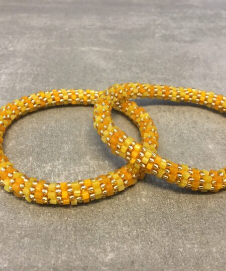 Roll-on armbånd som passer til næsten alle kvinder. Kvindegrupper i Nepal, Kathmandu Valley, udstyres med glasperler og bomuldsgarn, så de i deres fritid kan hækler disse smukke perlearmbånd. Den ekstra indtægt går bl.a. til at sende kvindernes børn i skole. Hvert armbånd er et unikt resultat af kvindernes håndarbejde og varierer i farvekombinationer og mønstre.