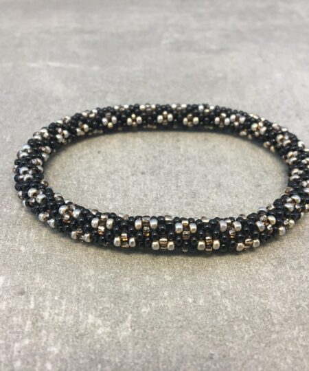 Roll-on armbånd som passer til næsten alle kvinder. Kvindegrupper i Nepal, Kathmandu Valley, udstyres med glasperler og bomuldsgarn, så de i deres fritid kan hækler disse smukke perlearmbånd. Den ekstra indtægt går bl.a. til at sende kvindernes børn i skole. Hvert armbånd er et unikt resultat af kvindernes håndarbejde og varierer i farvekombinationer og mønstre.