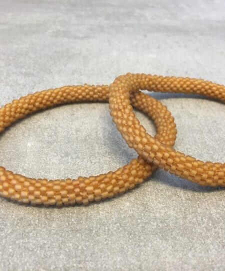 Roll-on armbånd som passer til næsten alle kvinder. Kvindegrupper i Nepal, Kathmandu Valley, udstyres med glasperler og bomuldsgarn, så de i deres fritid kan hækler disse smukke perlearmbånd. Den ekstra indtægt går bl.a. til at sende kvindernes børn i skole. Hvert armbånd er et unikt resultat af kvindernes håndarbejde og varierer i farvekombinationer og mønstre.