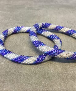 Roll-on armbånd som passer til næsten alle kvinder. Kvindegrupper i Nepal, Kathmandu Valley, udstyres med glasperler og bomuldsgarn, så de i deres fritid kan hækler disse smukke perlearmbånd. Den ekstra indtægt går bl.a. til at sende kvindernes børn i skole. Hvert armbånd er et unikt resultat af kvindernes håndarbejde og varierer i farvekombinationer og mønstre.