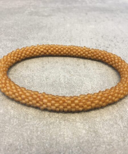 Roll-on armbånd som passer til næsten alle kvinder. Kvindegrupper i Nepal, Kathmandu Valley, udstyres med glasperler og bomuldsgarn, så de i deres fritid kan hækler disse smukke perlearmbånd. Den ekstra indtægt går bl.a. til at sende kvindernes børn i skole. Hvert armbånd er et unikt resultat af kvindernes håndarbejde og varierer i farvekombinationer og mønstre.