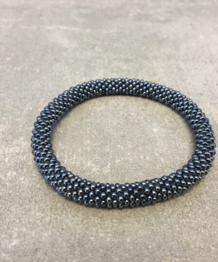 Roll-on armbånd som passer til næsten alle kvinder. Kvindegrupper i Nepal, Kathmandu Valley, udstyres med glasperler og bomuldsgarn, så de i deres fritid kan hækler disse smukke perlearmbånd. Den ekstra indtægt går bl.a. til at sende kvindernes børn i skole. Hvert armbånd er et unikt resultat af kvindernes håndarbejde og varierer i farvekombinationer og mønstre.