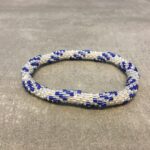 Roll-on armbånd som passer til næsten alle kvinder. Kvindegrupper i Nepal, Kathmandu Valley, udstyres med glasperler og bomuldsgarn, så de i deres fritid kan hækler disse smukke perlearmbånd. Den ekstra indtægt går bl.a. til at sende kvindernes børn i skole. Hvert armbånd er et unikt resultat af kvindernes håndarbejde og varierer i farvekombinationer og mønstre.