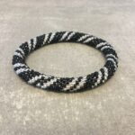 Roll-on armbånd som passer til næsten alle kvinder. Kvindegrupper i Nepal, Kathmandu Valley, udstyres med glasperler og bomuldsgarn, så de i deres fritid kan hækler disse smukke perlearmbånd. Den ekstra indtægt går bl.a. til at sende kvindernes børn i skole. Hvert armbånd er et unikt resultat af kvindernes håndarbejde og varierer i farvekombinationer og mønstre.