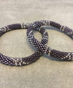 Roll-on armbånd som passer til næsten alle kvinder. Kvindegrupper i Nepal, Kathmandu Valley, udstyres med glasperler og bomuldsgarn, så de i deres fritid kan hækler disse smukke perlearmbånd. Den ekstra indtægt går bl.a. til at sende kvindernes børn i skole. Hvert armbånd er et unikt resultat af kvindernes håndarbejde og varierer i farvekombinationer og mønstre.