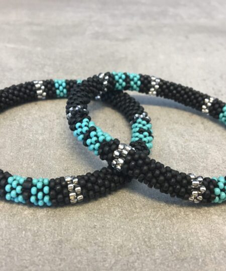 Roll-on armbånd som passer til næsten alle kvinder. Kvindegrupper i Nepal, Kathmandu Valley, udstyres med glasperler og bomuldsgarn, så de i deres fritid kan hækler disse smukke perlearmbånd. Den ekstra indtægt går bl.a. til at sende kvindernes børn i skole. Hvert armbånd er et unikt resultat af kvindernes håndarbejde og varierer i farvekombinationer og mønstre.