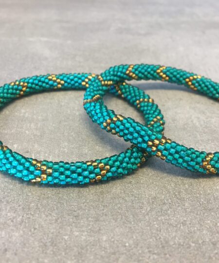 Roll-on armbånd som passer til næsten alle kvinder. Kvindegrupper i Nepal, Kathmandu Valley, udstyres med glasperler og bomuldsgarn, så de i deres fritid kan hækler disse smukke perlearmbånd. Den ekstra indtægt går bl.a. til at sende kvindernes børn i skole. Hvert armbånd er et unikt resultat af kvindernes håndarbejde og varierer i farvekombinationer og mønstre.