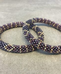 Roll-on armbånd som passer til næsten alle kvinder. Kvindegrupper i Nepal, Kathmandu Valley, udstyres med glasperler og bomuldsgarn, så de i deres fritid kan hækler disse smukke perlearmbånd. Den ekstra indtægt går bl.a. til at sende kvindernes børn i skole. Hvert armbånd er et unikt resultat af kvindernes håndarbejde og varierer i farvekombinationer og mønstre.