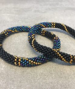 Roll-on armbånd som passer til næsten alle kvinder. Kvindegrupper i Nepal, Kathmandu Valley, udstyres med glasperler og bomuldsgarn, så de i deres fritid kan hækler disse smukke perlearmbånd. Den ekstra indtægt går bl.a. til at sende kvindernes børn i skole. Hvert armbånd er et unikt resultat af kvindernes håndarbejde og varierer i farvekombinationer og mønstre.