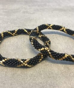 Roll-on armbånd som passer til næsten alle kvinder. Kvindegrupper i Nepal, Kathmandu Valley, udstyres med glasperler og bomuldsgarn, så de i deres fritid kan hækler disse smukke perlearmbånd. Den ekstra indtægt går bl.a. til at sende kvindernes børn i skole. Hvert armbånd er et unikt resultat af kvindernes håndarbejde og varierer i farvekombinationer og mønstre.