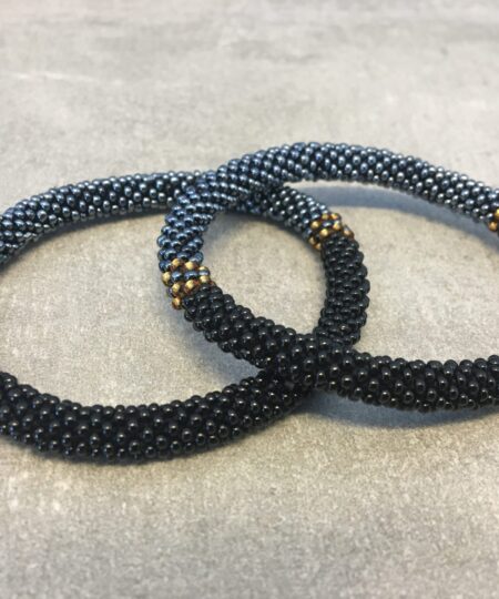 Roll-on armbånd som passer til næsten alle kvinder. Kvindegrupper i Nepal, Kathmandu Valley, udstyres med glasperler og bomuldsgarn, så de i deres fritid kan hækler disse smukke perlearmbånd. Den ekstra indtægt går bl.a. til at sende kvindernes børn i skole. Hvert armbånd er et unikt resultat af kvindernes håndarbejde og varierer i farvekombinationer og mønstre.