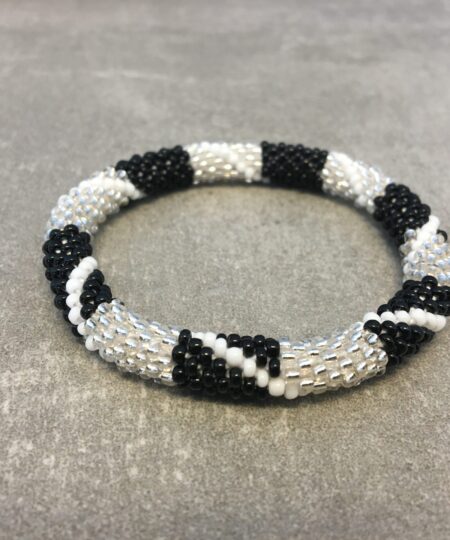 Roll-on armbånd som passer til næsten alle kvinder. Kvindegrupper i Nepal, Kathmandu Valley, udstyres med glasperler og bomuldsgarn, så de i deres fritid kan hækler disse smukke perlearmbånd. Den ekstra indtægt går bl.a. til at sende kvindernes børn i skole. Hvert armbånd er et unikt resultat af kvindernes håndarbejde og varierer i farvekombinationer og mønstre.