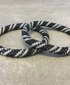 Roll-on armbånd som passer til næsten alle kvinder. Kvindegrupper i Nepal, Kathmandu Valley, udstyres med glasperler og bomuldsgarn, så de i deres fritid kan hækler disse smukke perlearmbånd. Den ekstra indtægt går bl.a. til at sende kvindernes børn i skole. Hvert armbånd er et unikt resultat af kvindernes håndarbejde og varierer i farvekombinationer og mønstre.