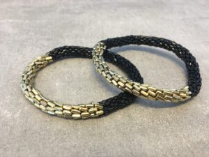 Roll-on armbånd som passer til næsten alle kvinder. Kvindegrupper i Nepal, Kathmandu Valley, udstyres med glasperler og bomuldsgarn, så de i deres fritid kan hækler disse smukke perlearmbånd. Den ekstra indtægt går bl.a. til at sende kvindernes børn i skole. Hvert armbånd er et unikt resultat af kvindernes håndarbejde og varierer i farvekombinationer og mønstre.