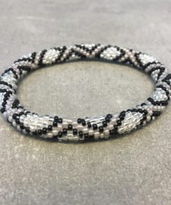 Roll-on armbånd som passer til næsten alle kvinder. Kvindegrupper i Nepal, Kathmandu Valley, udstyres med glasperler og bomuldsgarn, så de i deres fritid kan hækler disse smukke perlearmbånd. Den ekstra indtægt går bl.a. til at sende kvindernes børn i skole. Hvert armbånd er et unikt resultat af kvindernes håndarbejde og varierer i farvekombinationer og mønstre.