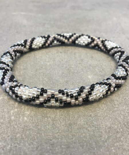 Roll-on armbånd som passer til næsten alle kvinder. Kvindegrupper i Nepal, Kathmandu Valley, udstyres med glasperler og bomuldsgarn, så de i deres fritid kan hækler disse smukke perlearmbånd. Den ekstra indtægt går bl.a. til at sende kvindernes børn i skole. Hvert armbånd er et unikt resultat af kvindernes håndarbejde og varierer i farvekombinationer og mønstre.