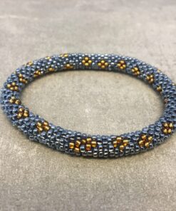 Roll-on armbånd som passer til næsten alle kvinder. Kvindegrupper i Nepal, Kathmandu Valley, udstyres med glasperler og bomuldsgarn, så de i deres fritid kan hækler disse smukke perlearmbånd. Den ekstra indtægt går bl.a. til at sende kvindernes børn i skole. Hvert armbånd er et unikt resultat af kvindernes håndarbejde og varierer i farvekombinationer og mønstre.