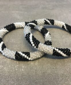 Roll-on armbånd som passer til næsten alle kvinder. Kvindegrupper i Nepal, Kathmandu Valley, udstyres med glasperler og bomuldsgarn, så de i deres fritid kan hækler disse smukke perlearmbånd. Den ekstra indtægt går bl.a. til at sende kvindernes børn i skole. Hvert armbånd er et unikt resultat af kvindernes håndarbejde og varierer i farvekombinationer og mønstre.