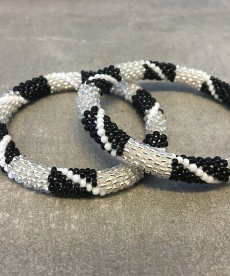 Roll-on armbånd som passer til næsten alle kvinder. Kvindegrupper i Nepal, Kathmandu Valley, udstyres med glasperler og bomuldsgarn, så de i deres fritid kan hækler disse smukke perlearmbånd. Den ekstra indtægt går bl.a. til at sende kvindernes børn i skole. Hvert armbånd er et unikt resultat af kvindernes håndarbejde og varierer i farvekombinationer og mønstre.