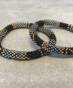 Roll-on armbånd som passer til næsten alle kvinder. Kvindegrupper i Nepal, Kathmandu Valley, udstyres med glasperler og bomuldsgarn, så de i deres fritid kan hækler disse smukke perlearmbånd. Den ekstra indtægt går bl.a. til at sende kvindernes børn i skole. Hvert armbånd er et unikt resultat af kvindernes håndarbejde og varierer i farvekombinationer og mønstre.