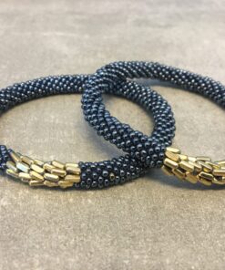 Roll-on armbånd som passer til næsten alle kvinder. Kvindegrupper i Nepal, Kathmandu Valley, udstyres med glasperler og bomuldsgarn, så de i deres fritid kan hækler disse smukke perlearmbånd. Den ekstra indtægt går bl.a. til at sende kvindernes børn i skole. Hvert armbånd er et unikt resultat af kvindernes håndarbejde og varierer i farvekombinationer og mønstre.