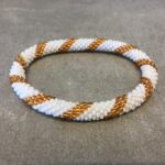 Roll-on armbånd som passer til næsten alle kvinder. Kvindegrupper i Nepal, Kathmandu Valley, udstyres med glasperler og bomuldsgarn, så de i deres fritid kan hækler disse smukke perlearmbånd. Den ekstra indtægt går bl.a. til at sende kvindernes børn i skole. Hvert armbånd er et unikt resultat af kvindernes håndarbejde og varierer i farvekombinationer og mønstre.