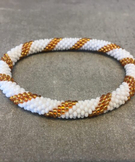 Roll-on armbånd som passer til næsten alle kvinder. Kvindegrupper i Nepal, Kathmandu Valley, udstyres med glasperler og bomuldsgarn, så de i deres fritid kan hækler disse smukke perlearmbånd. Den ekstra indtægt går bl.a. til at sende kvindernes børn i skole. Hvert armbånd er et unikt resultat af kvindernes håndarbejde og varierer i farvekombinationer og mønstre.