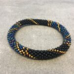 Roll-on armbånd som passer til næsten alle kvinder. Kvindegrupper i Nepal, Kathmandu Valley, udstyres med glasperler og bomuldsgarn, så de i deres fritid kan hækler disse smukke perlearmbånd. Den ekstra indtægt går bl.a. til at sende kvindernes børn i skole. Hvert armbånd er et unikt resultat af kvindernes håndarbejde og varierer i farvekombinationer og mønstre.