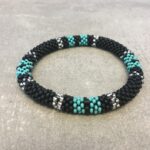 Roll-on armbånd som passer til næsten alle kvinder. Kvindegrupper i Nepal, Kathmandu Valley, udstyres med glasperler og bomuldsgarn, så de i deres fritid kan hækler disse smukke perlearmbånd. Den ekstra indtægt går bl.a. til at sende kvindernes børn i skole. Hvert armbånd er et unikt resultat af kvindernes håndarbejde og varierer i farvekombinationer og mønstre.