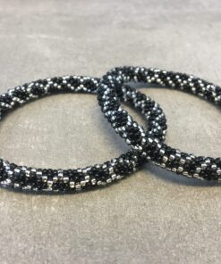 Roll-on armbånd som passer til næsten alle kvinder. Kvindegrupper i Nepal, Kathmandu Valley, udstyres med glasperler og bomuldsgarn, så de i deres fritid kan hækler disse smukke perlearmbånd. Den ekstra indtægt går bl.a. til at sende kvindernes børn i skole. Hvert armbånd er et unikt resultat af kvindernes håndarbejde og varierer i farvekombinationer og mønstre.