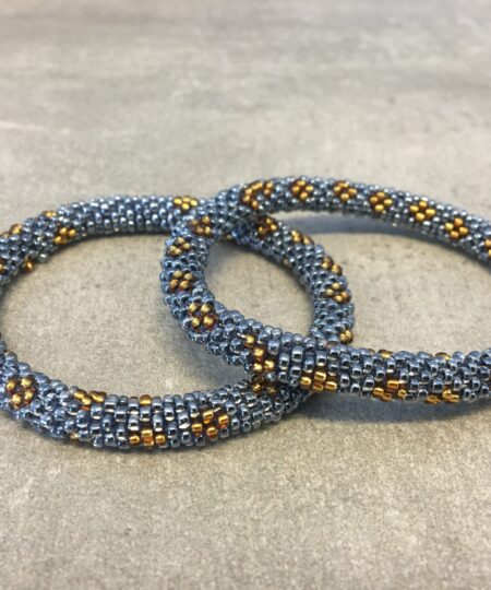 Roll-on armbånd som passer til næsten alle kvinder. Kvindegrupper i Nepal, Kathmandu Valley, udstyres med glasperler og bomuldsgarn, så de i deres fritid kan hækler disse smukke perlearmbånd. Den ekstra indtægt går bl.a. til at sende kvindernes børn i skole. Hvert armbånd er et unikt resultat af kvindernes håndarbejde og varierer i farvekombinationer og mønstre.