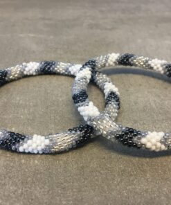 Roll-on armbånd som passer til næsten alle kvinder. Kvindegrupper i Nepal, Kathmandu Valley, udstyres med glasperler og bomuldsgarn, så de i deres fritid kan hækler disse smukke perlearmbånd. Den ekstra indtægt går bl.a. til at sende kvindernes børn i skole. Hvert armbånd er et unikt resultat af kvindernes håndarbejde og varierer i farvekombinationer og mønstre.