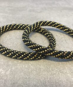 Roll-on armbånd som passer til næsten alle kvinder. Kvindegrupper i Nepal, Kathmandu Valley, udstyres med glasperler og bomuldsgarn, så de i deres fritid kan hækler disse smukke perlearmbånd. Den ekstra indtægt går bl.a. til at sende kvindernes børn i skole. Hvert armbånd er et unikt resultat af kvindernes håndarbejde og varierer i farvekombinationer og mønstre.