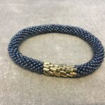 Roll-on armbånd som passer til næsten alle kvinder. Kvindegrupper i Nepal, Kathmandu Valley, udstyres med glasperler og bomuldsgarn, så de i deres fritid kan hækler disse smukke perlearmbånd. Den ekstra indtægt går bl.a. til at sende kvindernes børn i skole. Hvert armbånd er et unikt resultat af kvindernes håndarbejde og varierer i farvekombinationer og mønstre.