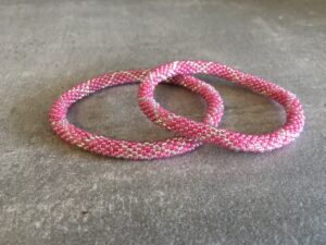 Roll-on perle armbåndene er håndlavet i Nepal. De er lavet med forskellige glasperler og i forskellige mønster. De er hæklet med en bomuldssnor. Syntes man at de lidt stramme, kan man vride forsigtigt i dem så de bliver større. syntes man derimod at de er blive lidt for løse, kan man ligge dem i vand. dette gør at bomildssnoren trækker sig sammen og de bliver mindre igen.