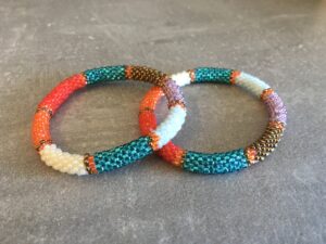 Roll-on perle armbåndene er håndlavet i Nepal. De er lavet med forskellige glasperler og i forskellige mønster. De er hæklet med en bomuldssnor. Syntes man at de lidt stramme, kan man vride forsigtigt i dem så de bliver større. syntes man derimod at de er blive lidt for løse, kan man ligge dem i vand. dette gør at bomildssnoren trækker sig sammen og de bliver mindre igen.