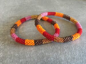 Roll-on perle armbåndene er håndlavet i Nepal. De er lavet med forskellige glasperler og i forskellige mønster. De er hæklet med en bomuldssnor. Syntes man at de lidt stramme, kan man vride forsigtigt i dem så de bliver større. syntes man derimod at de er blive lidt for løse, kan man ligge dem i vand. dette gør at bomildssnoren trækker sig sammen og de bliver mindre igen.