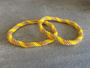Roll-on perle armbåndene er håndlavet i Nepal. De er lavet med forskellige glasperler og i forskellige mønster. De er hæklet med en bomuldssnor. Syntes man at de lidt stramme, kan man vride forsigtigt i dem så de bliver større. syntes man derimod at de er blive lidt for løse, kan man ligge dem i vand. dette gør at bomildssnoren trækker sig sammen og de bliver mindre igen.