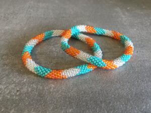 Roll-on perle armbåndene er håndlavet i Nepal. De er lavet med forskellige glasperler og i forskellige mønster. De er hæklet med en bomuldssnor. Syntes man at de lidt stramme, kan man vride forsigtigt i dem så de bliver større. syntes man derimod at de er blive lidt for løse, kan man ligge dem i vand. dette gør at bomildssnoren trækker sig sammen og de bliver mindre igen.