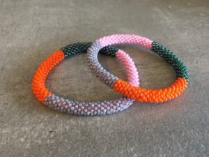 Roll-on perle armbåndene er håndlavet i Nepal. De er lavet med forskellige glasperler og i forskellige mønster. De er hæklet med en bomuldssnor. Syntes man at de lidt stramme, kan man vride forsigtigt i dem så de bliver større. syntes man derimod at de er blive lidt for løse, kan man ligge dem i vand. dette gør at bomildssnoren trækker sig sammen og de bliver mindre igen.