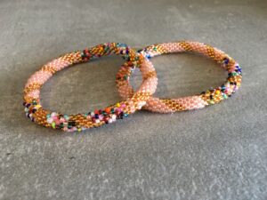 Roll-on perle armbåndene er håndlavet i Nepal. De er lavet med forskellige glasperler og i forskellige mønster. De er hæklet med en bomuldssnor. Syntes man at de lidt stramme, kan man vride forsigtigt i dem så de bliver større. syntes man derimod at de er blive lidt for løse, kan man ligge dem i vand. dette gør at bomildssnoren trækker sig sammen og de bliver mindre igen.