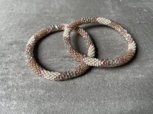 Nepal perle armbånd Nepal armbånd er en inspirerende og fascinerende smykkegenre, der vækker interessen hos smykkeentusiaster over hele verden. Disse håndlavede armbånd er kunstværker, der udstråler autenticitet, skønhed og dyb symbolik. Lad os dykke ned i den betagende verden af Nepal armbånd og udforske, hvad der gør dem så unikke og eftertragtede. Hvert Nepal armbånd er unikt, og det er netop denne individualitet, der appellerer til mange. Armbåndene er ofte skabt af dygtige nepalesiske håndværkere, der gennem generationer har forfinet deres teknikker til at skabe smykker af høj kvalitet. Disse håndværkere bruger traditionelle metoder, som har været en del af Nepals kultur og historie i århundreder. Processen er omhyggelig og kræver en stor grad af præcision og tålmodighed, hvilket gør hvert armbånd til en kærlighedsfyldt skabelse. Nepal armbånd er kendt for deres farverige og levende design. De er ofte dekoreret med perler, ædelstene, træ, metal eller andre naturlige materialer, hvilket giver dem et unikt udseende. Hvert enkelt element, der anvendes i armbåndene, er udvalgt omhyggeligt for at skabe en harmonisk kombination af farver og teksturer. Disse elementer er ofte inspireret af Nepals rige natur og kultur, hvilket giver armbåndene en autentisk følelse og en stærk forbindelse til landet. Symbolik spiller også en vigtig rolle i Nepal armbåndenes popularitet. Mange af armbåndene har indgraverede mønstre eller symboler, der repræsenterer vigtige aspekter af Nepals traditioner og spiritualitet. Disse symboler kan have betydning for held, lykke, kærlighed, beskyttelse eller en dybere forbindelse til naturen. At bære et Nepal armbånd kan derfor have en dybere betydning for bæreren og kan fungere som en påmindelse om deres forbindelse til Nepals rige arv. Nepal armbånd er ikke kun smukke smykker, men de har også en stærk social og kulturel betydning. Mange af disse smykker er håndlavede af kvinder, der er en del af samfundet i landområderne i Nepal. Produktionen af armbåndene giver disse kvinder mulighed for at skabe en bæredygtig indkomst, forbedre deres levevilkår og styrke deres selvstændighed. Når du køber et Nepal armbånd, bidrager du derfor til at støtte en positiv social indvirkning og bevare traditionelle håndværksmæssige metoder. Udover deres kulturelle og sociale betydning er Nepal armbånd også en favorit blandt modebevidste enkeltpersoner, der ønsker at tilføje en unik og autentisk touch til deres stil. Disse armbånd kan styles på utallige måder, uanset om du ønsker at skabe et bohemeinspireret look, en farverig festlig stil eller en subtil og elegant kombination. Der er et Nepal armbånd til enhver lejlighed og enhver personlig præference. I det store udvalg af smykker, der findes i dagens marked, skiller Nepal armbånd sig ud som en særlig perle. Deres håndlavede karakter, farverige design, dybe symbolik og sociale indvirkning gør dem til mere end bare smykker - de er en form for kunst og kultur, der fortæller historien om Nepal og dets folk. Ved at bære et Nepal armbånd, bærer du også med dig en del af dette rige og inspirerende land. Så uanset om du leder efter en meningsfuld gave eller ønsker at berige din egen smykkesamling, vil et Nepal armbånd være et mindeværdigt og værdsat valg.