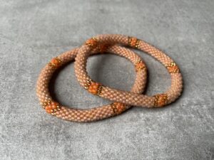 Nepal perle armbånd Nepal armbånd er en inspirerende og fascinerende smykkegenre, der vækker interessen hos smykkeentusiaster over hele verden. Disse håndlavede armbånd er kunstværker, der udstråler autenticitet, skønhed og dyb symbolik. Lad os dykke ned i den betagende verden af Nepal armbånd og udforske, hvad der gør dem så unikke og eftertragtede. Hvert Nepal armbånd er unikt, og det er netop denne individualitet, der appellerer til mange. Armbåndene er ofte skabt af dygtige nepalesiske håndværkere, der gennem generationer har forfinet deres teknikker til at skabe smykker af høj kvalitet. Disse håndværkere bruger traditionelle metoder, som har været en del af Nepals kultur og historie i århundreder. Processen er omhyggelig og kræver en stor grad af præcision og tålmodighed, hvilket gør hvert armbånd til en kærlighedsfyldt skabelse. Nepal armbånd er kendt for deres farverige og levende design. De er ofte dekoreret med perler, ædelstene, træ, metal eller andre naturlige materialer, hvilket giver dem et unikt udseende. Hvert enkelt element, der anvendes i armbåndene, er udvalgt omhyggeligt for at skabe en harmonisk kombination af farver og teksturer. Disse elementer er ofte inspireret af Nepals rige natur og kultur, hvilket giver armbåndene en autentisk følelse og en stærk forbindelse til landet. Symbolik spiller også en vigtig rolle i Nepal armbåndenes popularitet. Mange af armbåndene har indgraverede mønstre eller symboler, der repræsenterer vigtige aspekter af Nepals traditioner og spiritualitet. Disse symboler kan have betydning for held, lykke, kærlighed, beskyttelse eller en dybere forbindelse til naturen. At bære et Nepal armbånd kan derfor have en dybere betydning for bæreren og kan fungere som en påmindelse om deres forbindelse til Nepals rige arv. Nepal armbånd er ikke kun smukke smykker, men de har også en stærk social og kulturel betydning. Mange af disse smykker er håndlavede af kvinder, der er en del af samfundet i landområderne i Nepal. Produktionen af armbåndene giver disse kvinder mulighed for at skabe en bæredygtig indkomst, forbedre deres levevilkår og styrke deres selvstændighed. Når du køber et Nepal armbånd, bidrager du derfor til at støtte en positiv social indvirkning og bevare traditionelle håndværksmæssige metoder. Udover deres kulturelle og sociale betydning er Nepal armbånd også en favorit blandt modebevidste enkeltpersoner, der ønsker at tilføje en unik og autentisk touch til deres stil. Disse armbånd kan styles på utallige måder, uanset om du ønsker at skabe et bohemeinspireret look, en farverig festlig stil eller en subtil og elegant kombination. Der er et Nepal armbånd til enhver lejlighed og enhver personlig præference. I det store udvalg af smykker, der findes i dagens marked, skiller Nepal armbånd sig ud som en særlig perle. Deres håndlavede karakter, farverige design, dybe symbolik og sociale indvirkning gør dem til mere end bare smykker - de er en form for kunst og kultur, der fortæller historien om Nepal og dets folk. Ved at bære et Nepal armbånd, bærer du også med dig en del af dette rige og inspirerende land. Så uanset om du leder efter en meningsfuld gave eller ønsker at berige din egen smykkesamling, vil et Nepal armbånd være et mindeværdigt og værdsat valg.