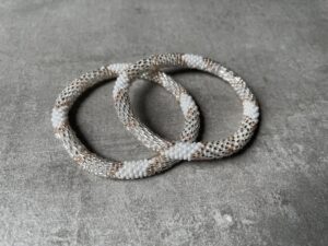 Nepal perle armbånd Nepal armbånd er en inspirerende og fascinerende smykkegenre, der vækker interessen hos smykkeentusiaster over hele verden. Disse håndlavede armbånd er kunstværker, der udstråler autenticitet, skønhed og dyb symbolik. Lad os dykke ned i den betagende verden af Nepal armbånd og udforske, hvad der gør dem så unikke og eftertragtede. Hvert Nepal armbånd er unikt, og det er netop denne individualitet, der appellerer til mange. Armbåndene er ofte skabt af dygtige nepalesiske håndværkere, der gennem generationer har forfinet deres teknikker til at skabe smykker af høj kvalitet. Disse håndværkere bruger traditionelle metoder, som har været en del af Nepals kultur og historie i århundreder. Processen er omhyggelig og kræver en stor grad af præcision og tålmodighed, hvilket gør hvert armbånd til en kærlighedsfyldt skabelse. Nepal armbånd er kendt for deres farverige og levende design. De er ofte dekoreret med perler, ædelstene, træ, metal eller andre naturlige materialer, hvilket giver dem et unikt udseende. Hvert enkelt element, der anvendes i armbåndene, er udvalgt omhyggeligt for at skabe en harmonisk kombination af farver og teksturer. Disse elementer er ofte inspireret af Nepals rige natur og kultur, hvilket giver armbåndene en autentisk følelse og en stærk forbindelse til landet. Symbolik spiller også en vigtig rolle i Nepal armbåndenes popularitet. Mange af armbåndene har indgraverede mønstre eller symboler, der repræsenterer vigtige aspekter af Nepals traditioner og spiritualitet. Disse symboler kan have betydning for held, lykke, kærlighed, beskyttelse eller en dybere forbindelse til naturen. At bære et Nepal armbånd kan derfor have en dybere betydning for bæreren og kan fungere som en påmindelse om deres forbindelse til Nepals rige arv. Nepal armbånd er ikke kun smukke smykker, men de har også en stærk social og kulturel betydning. Mange af disse smykker er håndlavede af kvinder, der er en del af samfundet i landområderne i Nepal. Produktionen af armbåndene giver disse kvinder mulighed for at skabe en bæredygtig indkomst, forbedre deres levevilkår og styrke deres selvstændighed. Når du køber et Nepal armbånd, bidrager du derfor til at støtte en positiv social indvirkning og bevare traditionelle håndværksmæssige metoder. Udover deres kulturelle og sociale betydning er Nepal armbånd også en favorit blandt modebevidste enkeltpersoner, der ønsker at tilføje en unik og autentisk touch til deres stil. Disse armbånd kan styles på utallige måder, uanset om du ønsker at skabe et bohemeinspireret look, en farverig festlig stil eller en subtil og elegant kombination. Der er et Nepal armbånd til enhver lejlighed og enhver personlig præference. I det store udvalg af smykker, der findes i dagens marked, skiller Nepal armbånd sig ud som en særlig perle. Deres håndlavede karakter, farverige design, dybe symbolik og sociale indvirkning gør dem til mere end bare smykker - de er en form for kunst og kultur, der fortæller historien om Nepal og dets folk. Ved at bære et Nepal armbånd, bærer du også med dig en del af dette rige og inspirerende land. Så uanset om du leder efter en meningsfuld gave eller ønsker at berige din egen smykkesamling, vil et Nepal armbånd være et mindeværdigt og værdsat valg.